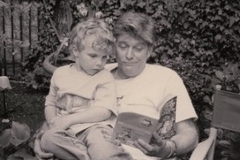 Ross reading to a young Noah in a sunlit garden